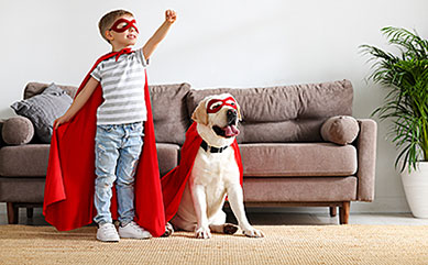 child dressed as superhero playing with his dog 